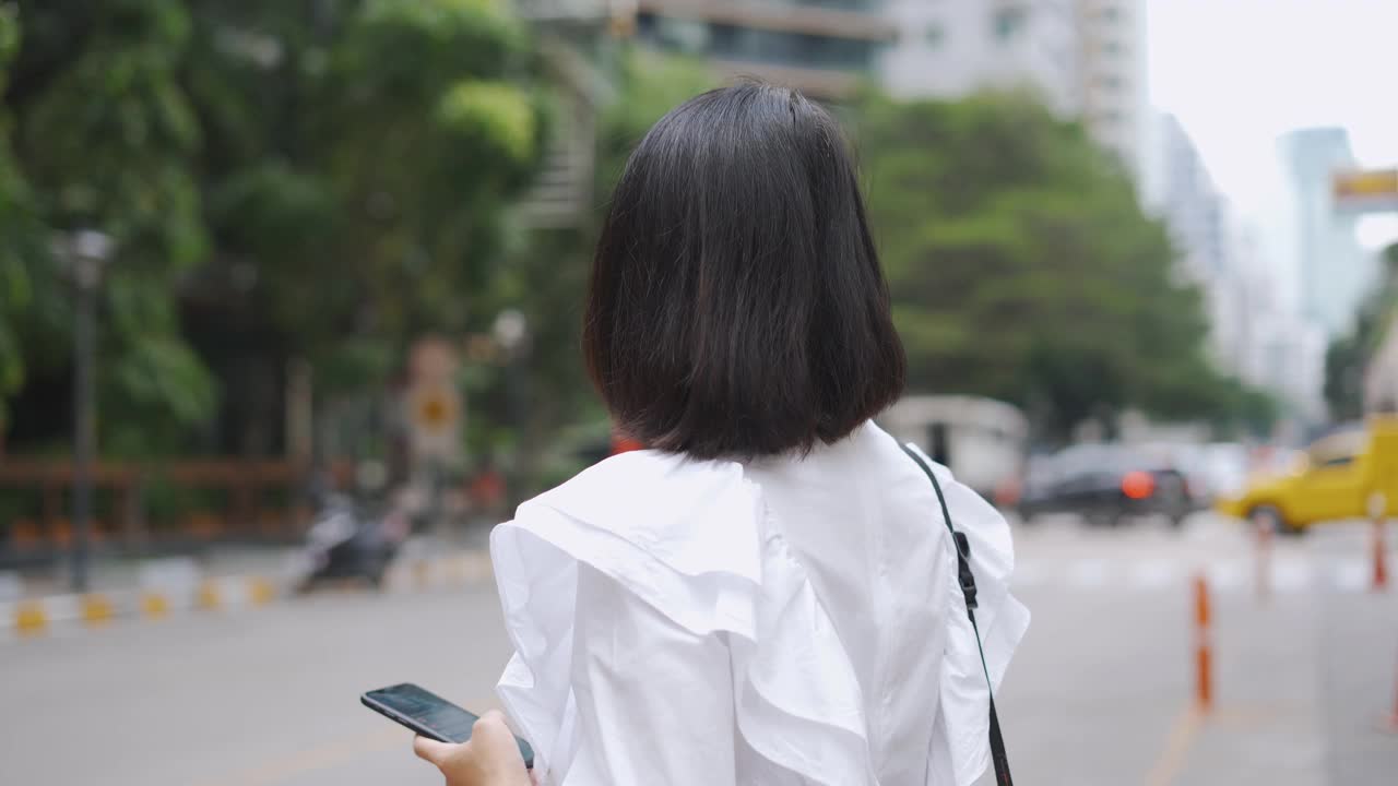 亚洲女商人在等出租车时使用手机视频素材