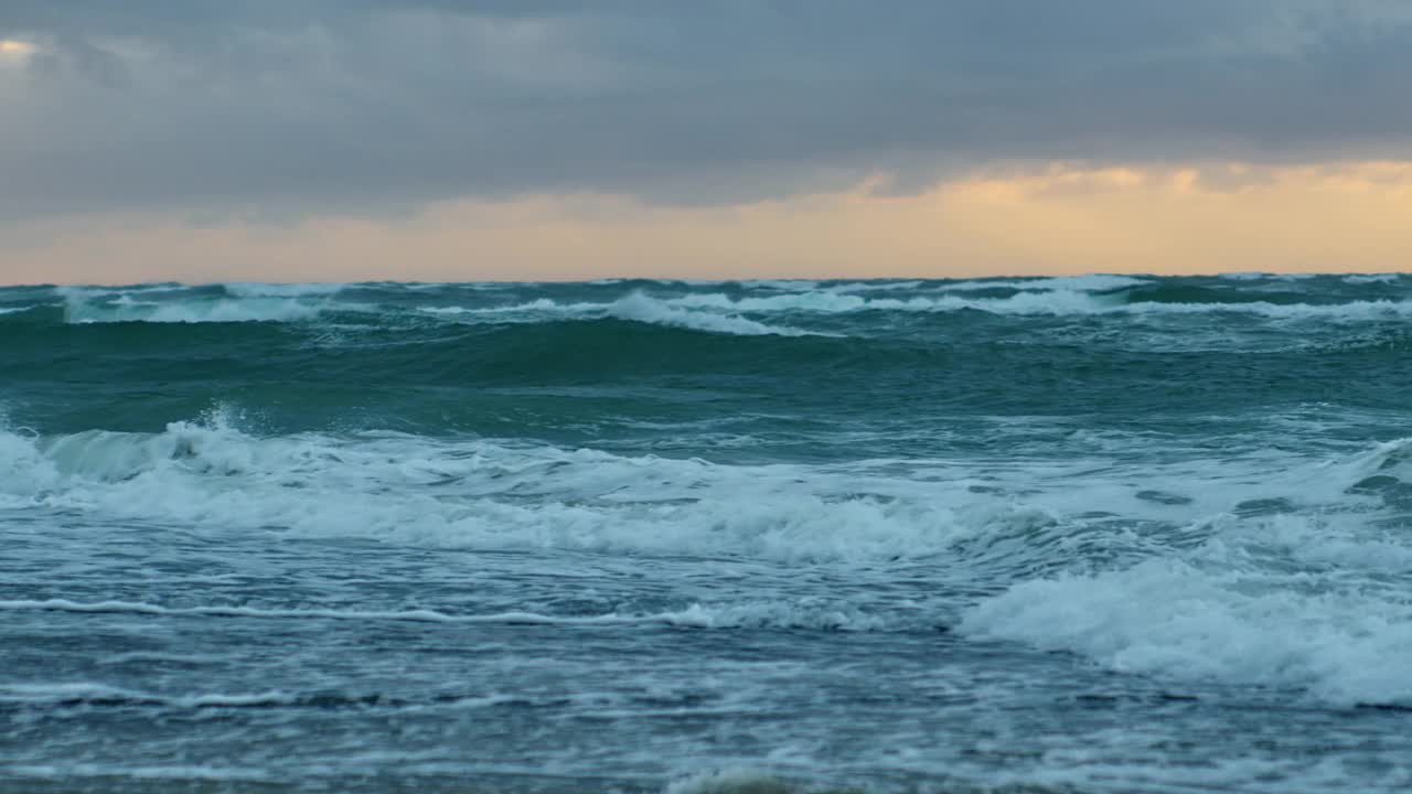 在日落的天空下海浪翻滚到海滩上视频素材