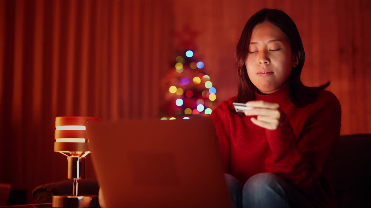 年轻女子在圣诞节晚上在家用笔记本电脑网购视频素材