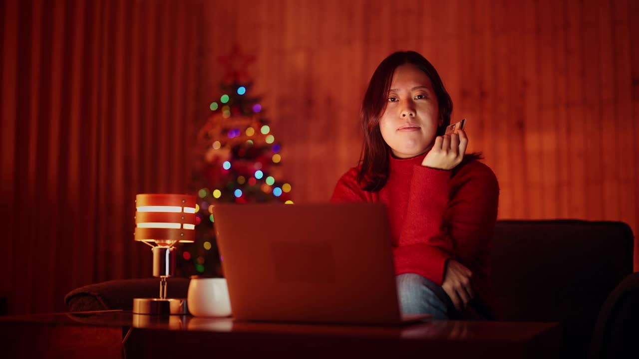 年轻女子在圣诞节晚上在家用笔记本电脑网购视频素材