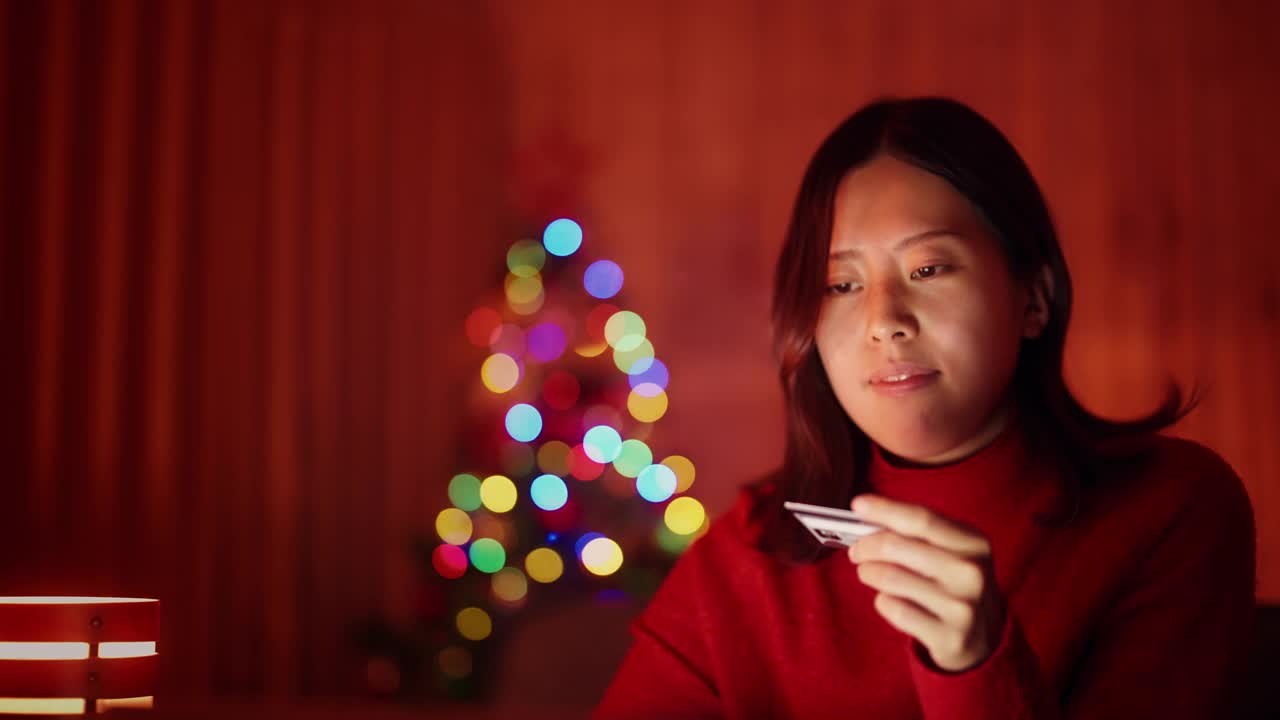 年轻女子在圣诞节晚上在家用笔记本电脑网购视频素材