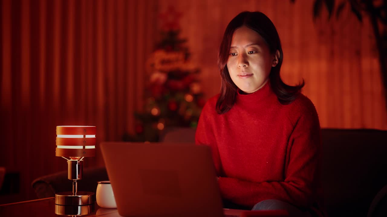 年轻女子在圣诞节晚上在家用笔记本电脑网购视频素材