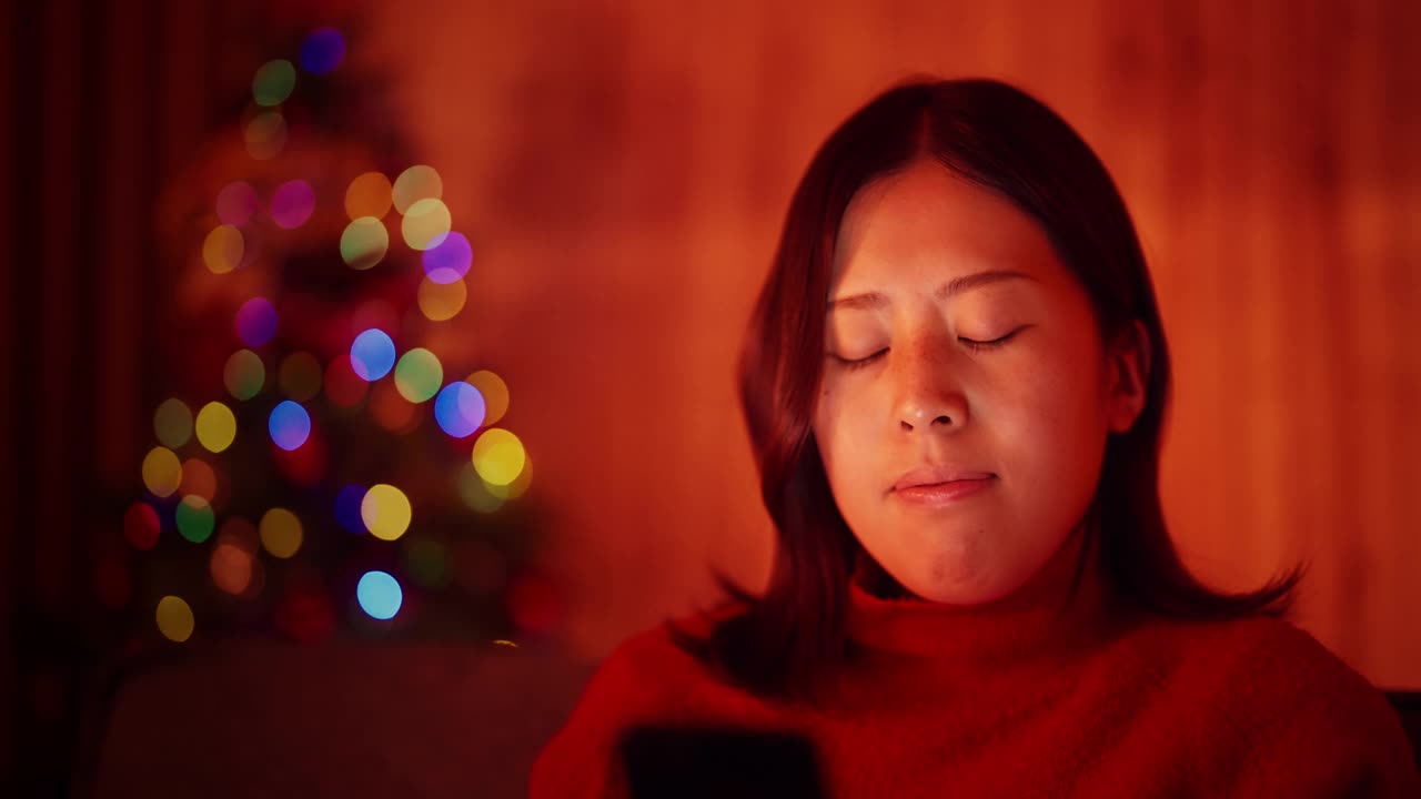 一名年轻女子在圣诞节晚上在家用智能手机网购视频素材