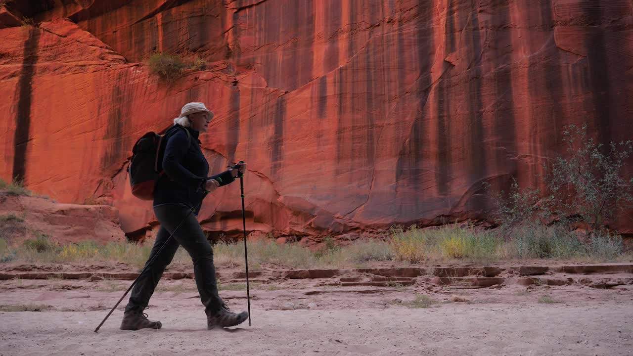 徒步旅行者在红色岩石形成的槽峡谷的沙干河床上徒步旅行视频素材