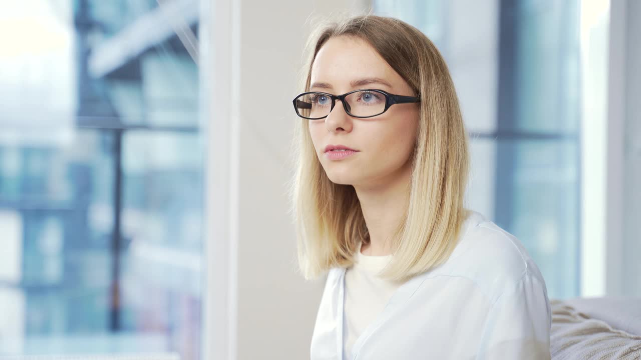 特写的一个年轻的成年金发商业妇女与眼镜看着相机视频素材