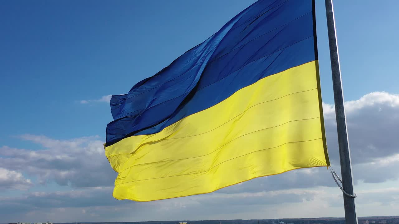 在晴空万里的背景下，乌克兰国旗在旗杆上飘扬视频素材