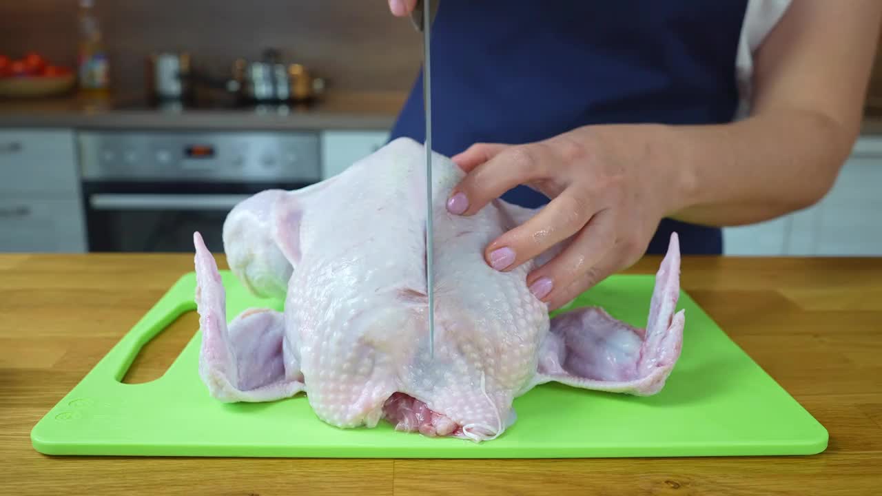 女厨师在砧板上切生鸡肉。烤鸡制作工艺视频素材