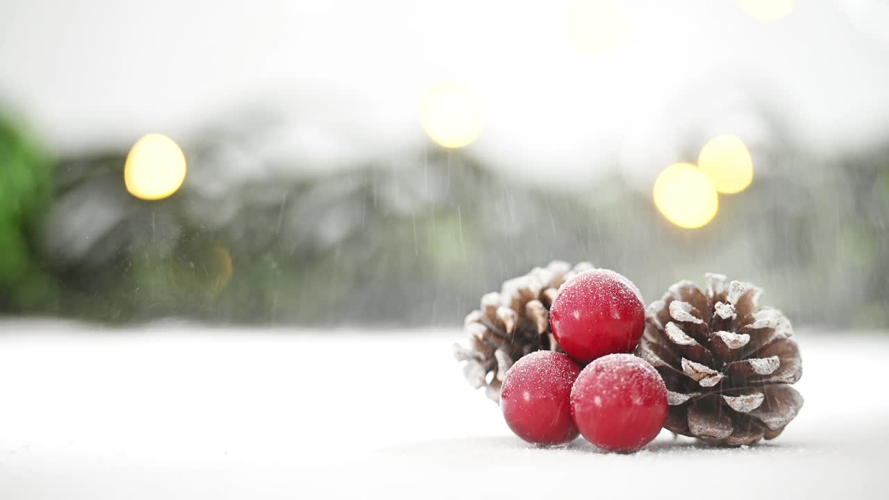 靠近冬青和松果上的雪，背景是灯光和树枝视频素材