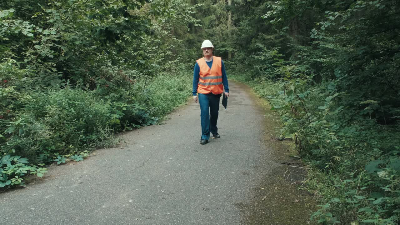 穿着工作服戴着头盔的工人在森林的高速公路上视频素材