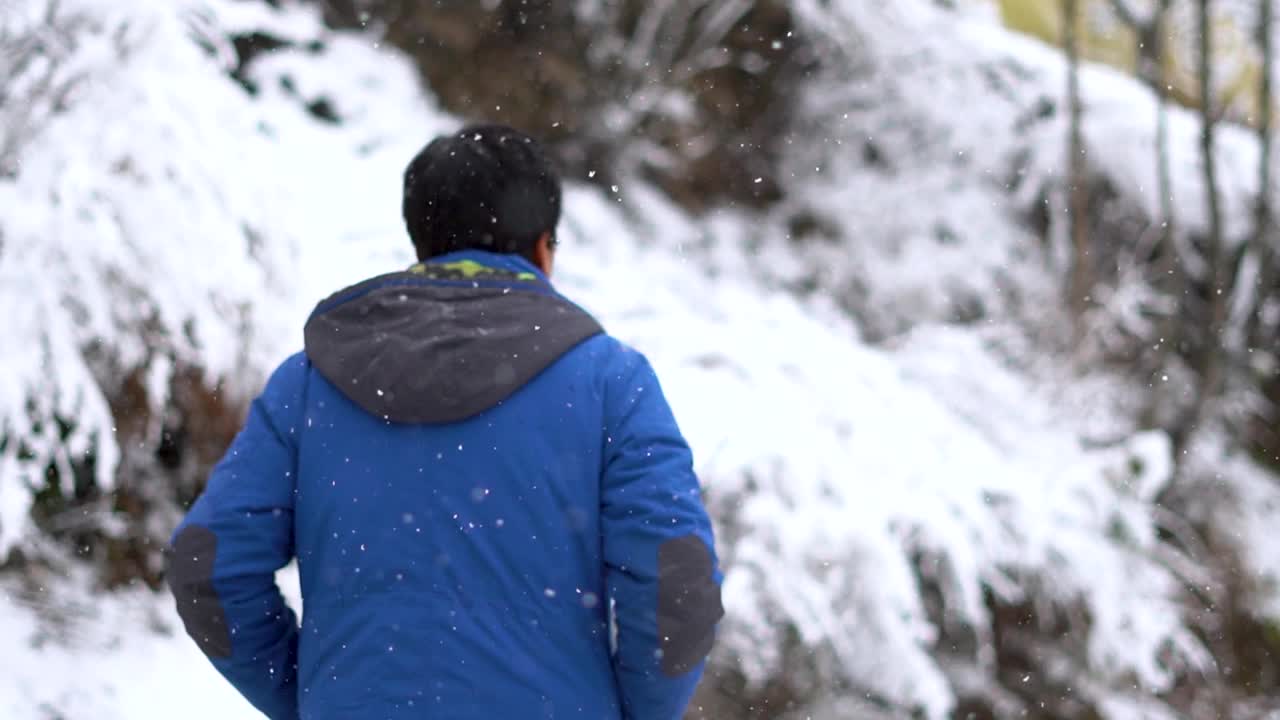 在印度喜马偕尔邦的马纳里，一名印度男子在大雪中走在被积雪覆盖的道路上的慢动作肖像。视频素材