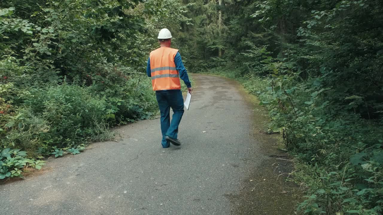 穿着工作服戴着头盔的工人在森林的高速公路上视频素材