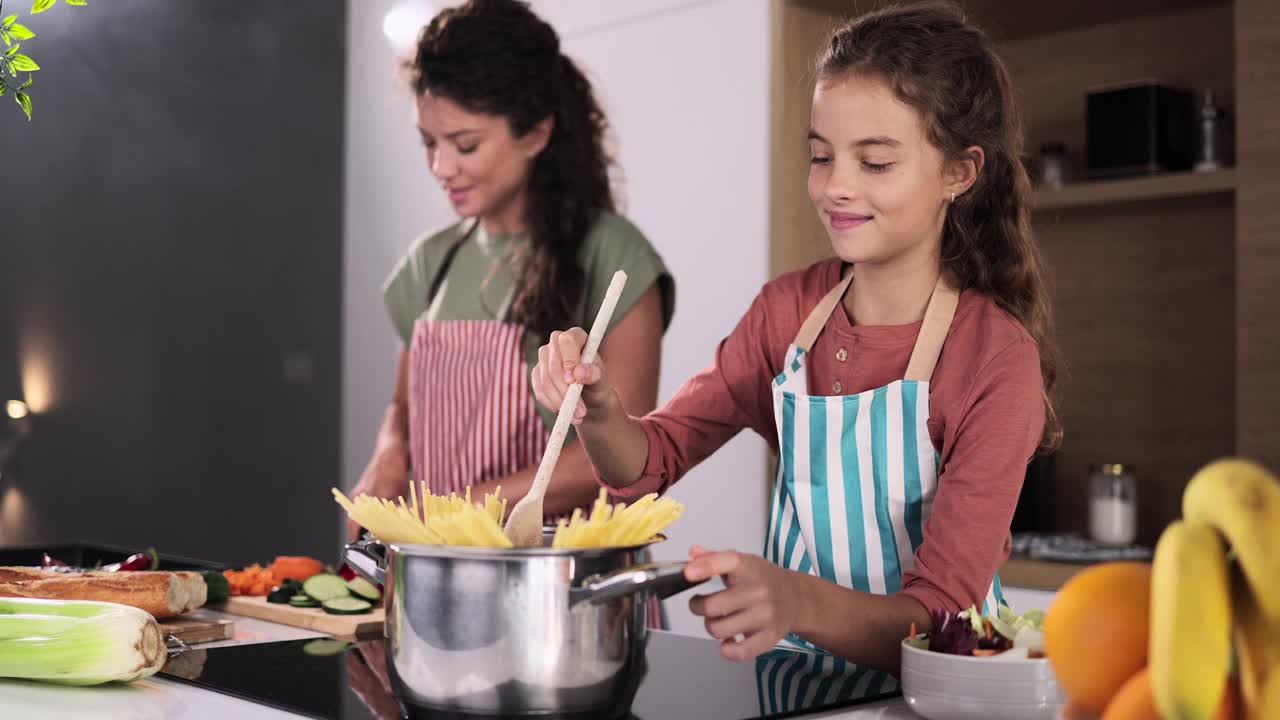 快乐的单身母亲和她年幼的女儿一起做饭。视频素材