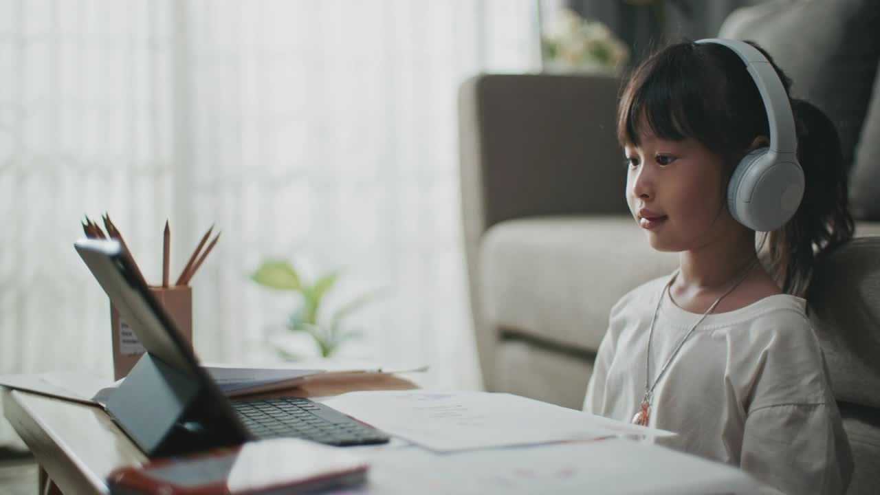 家庭学校快乐微笑的小女孩有视频通话的平板电脑和显示她的绘画在家里视频素材