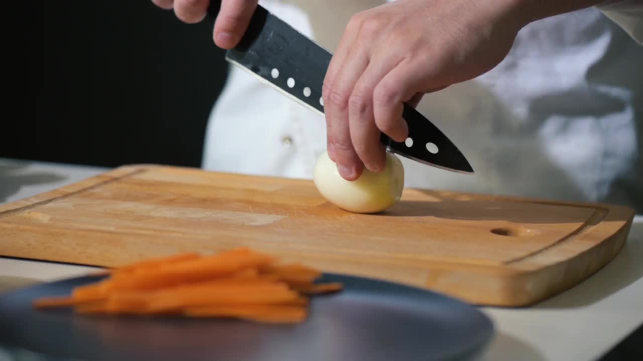 厨师在砧板上用刀将洋葱切成片，做蔬菜沙拉用视频素材