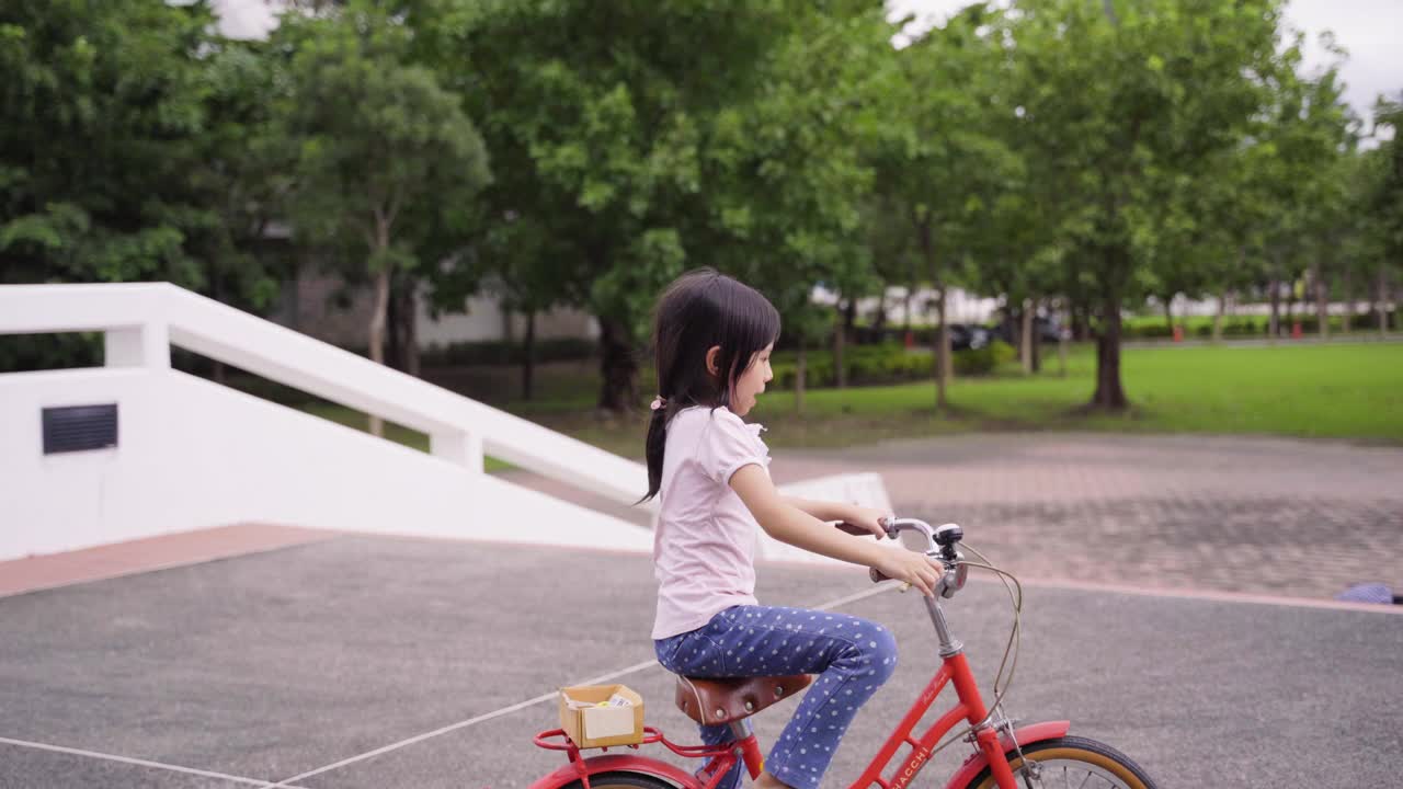 亚洲可爱女孩学习骑自行车视频素材