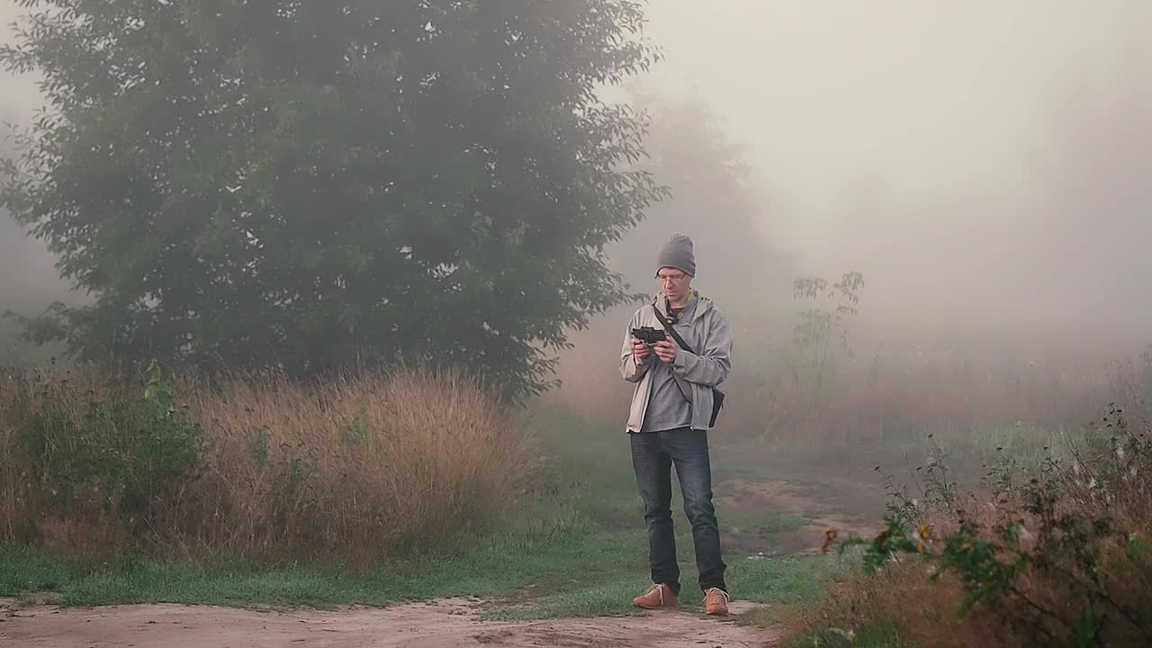 清晨，一名手持无人机遥控器的男子站在户外视频素材