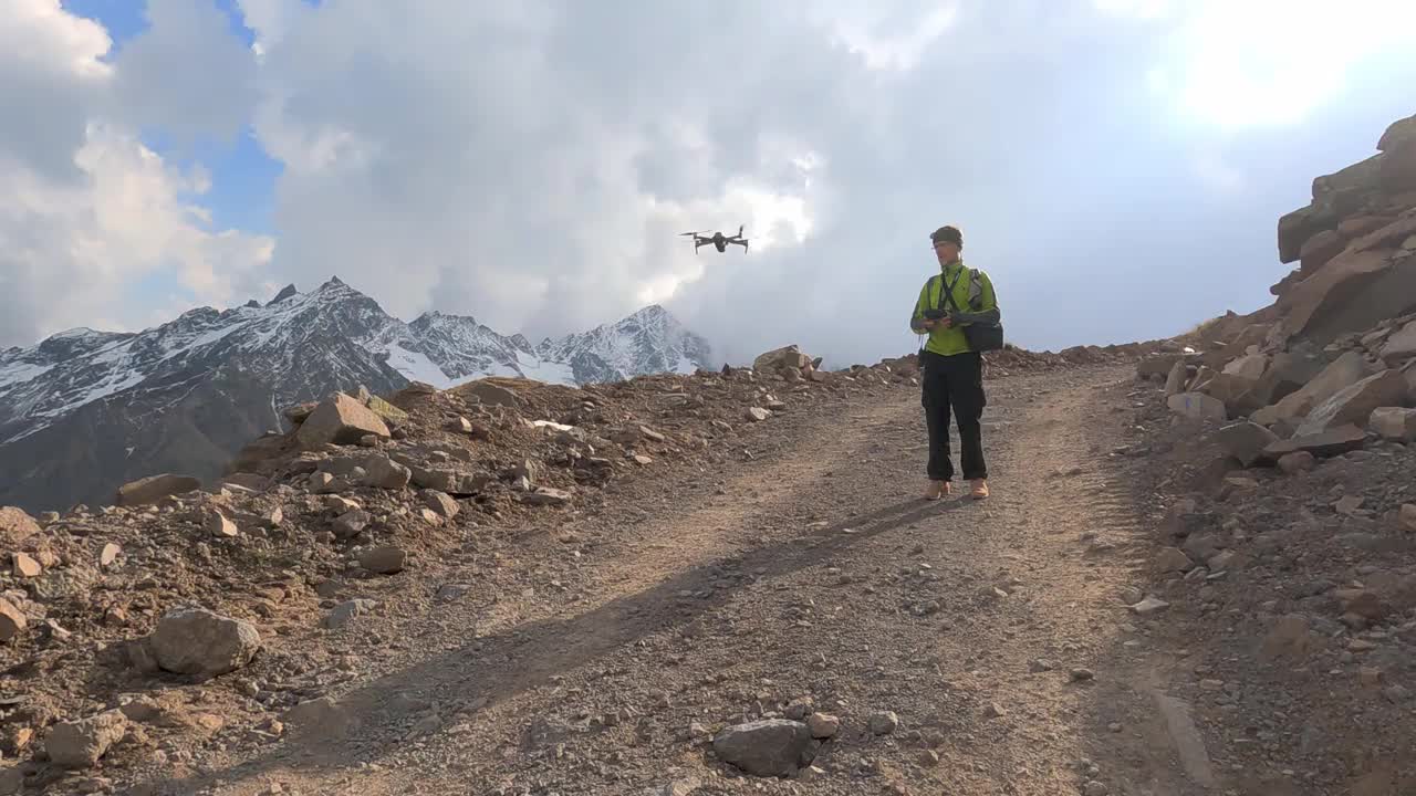 一名遥控男子看着无人机降落在埃尔布鲁斯山区的公路上视频素材