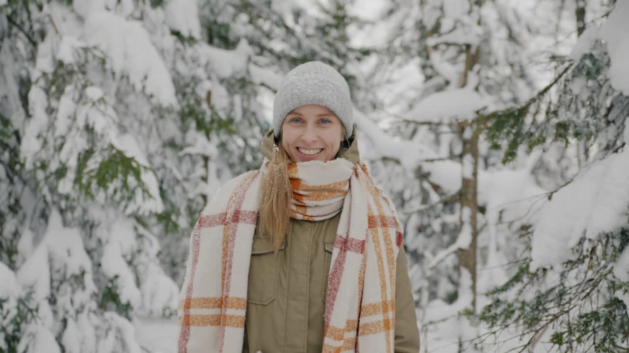 快乐的年轻女游客的肖像站在冰雪覆盖的冬季森林视频素材