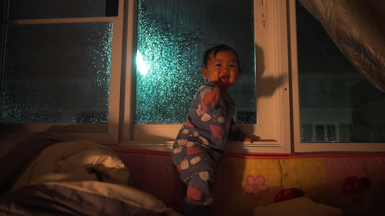 幸福时刻亚裔母女望着窗外下雨，等待父亲回家的家庭生活视频素材