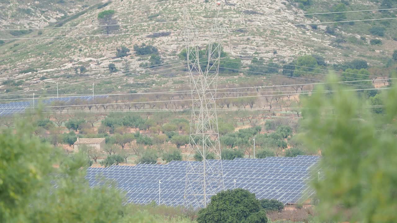 田间的太阳能电池板带有高压电塔。视频素材