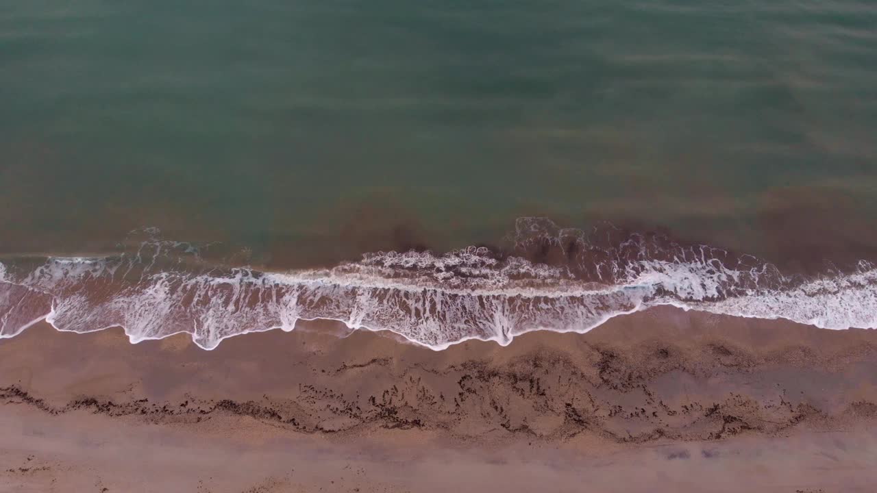 空的热带沙滩与海浪，俯视图。日落时海浪拍打着沙滩。美丽的海景视频素材