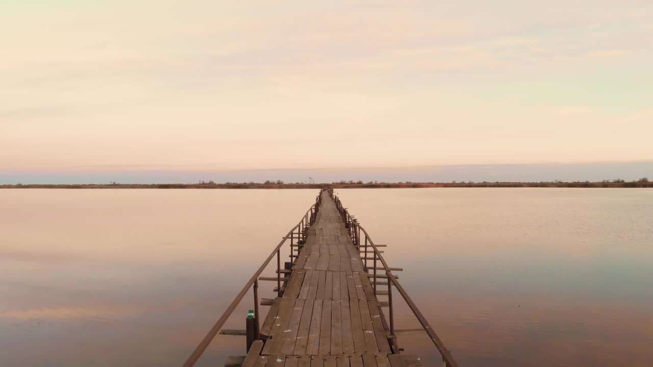 日出时美丽的湖面。河口上的空木桥。美丽的野生自然景观视频素材