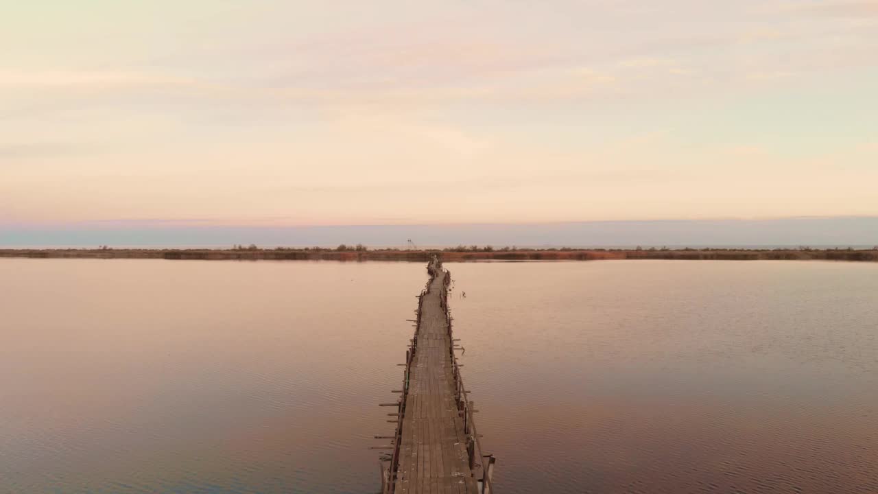 夕阳西下，空木桥横跨宁静的湖面。河口日出时。美丽的大自然。乡村景观视频素材