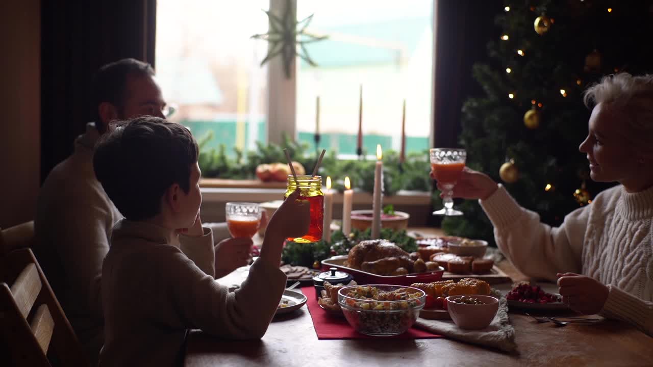 欢乐的白种人家庭和可爱的小男孩在圣诞餐桌上碰杯祝酒。视频素材