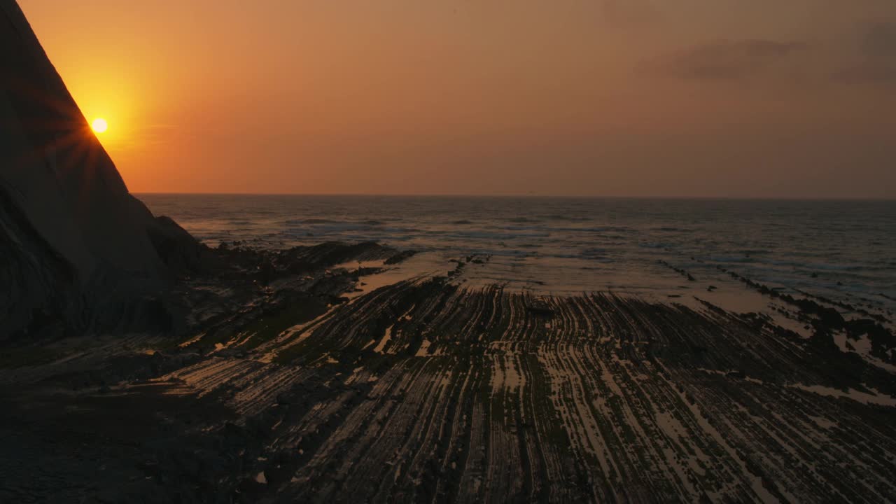 太阳在日落时躲在山后的海边视频素材