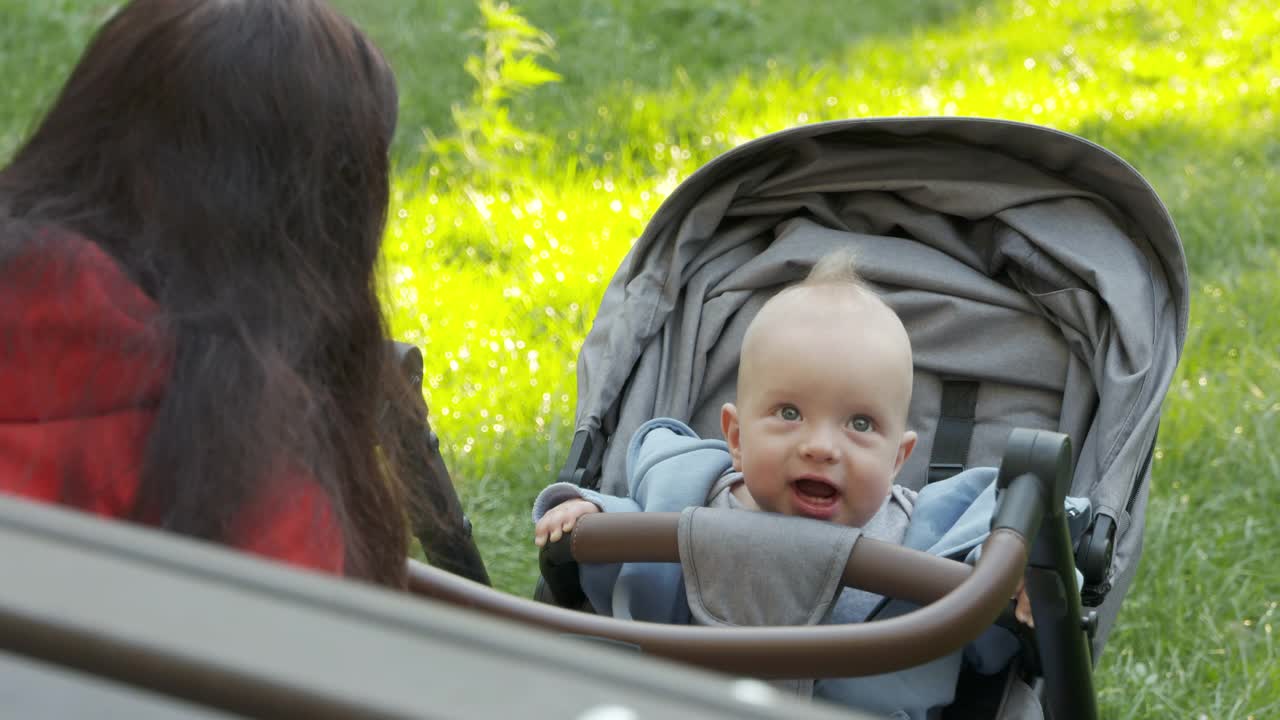 妈妈和她快乐的宝宝在户外，夏天的一天，妈妈和六个月大的宝宝在公园里玩。视频素材