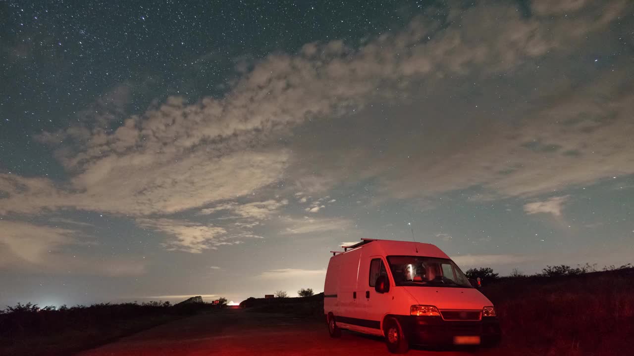 法国，布列塔尼，夜空中的星星下移动的云，在前景中的露营车旁边视频素材