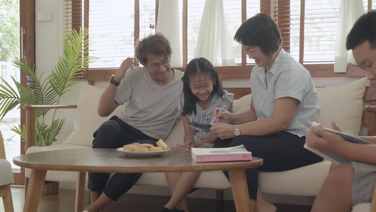 一家人坐在客厅里，用着电子平板电脑视频素材