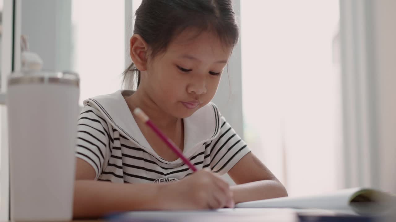 亚洲小女孩在家学习用铅笔写字视频素材