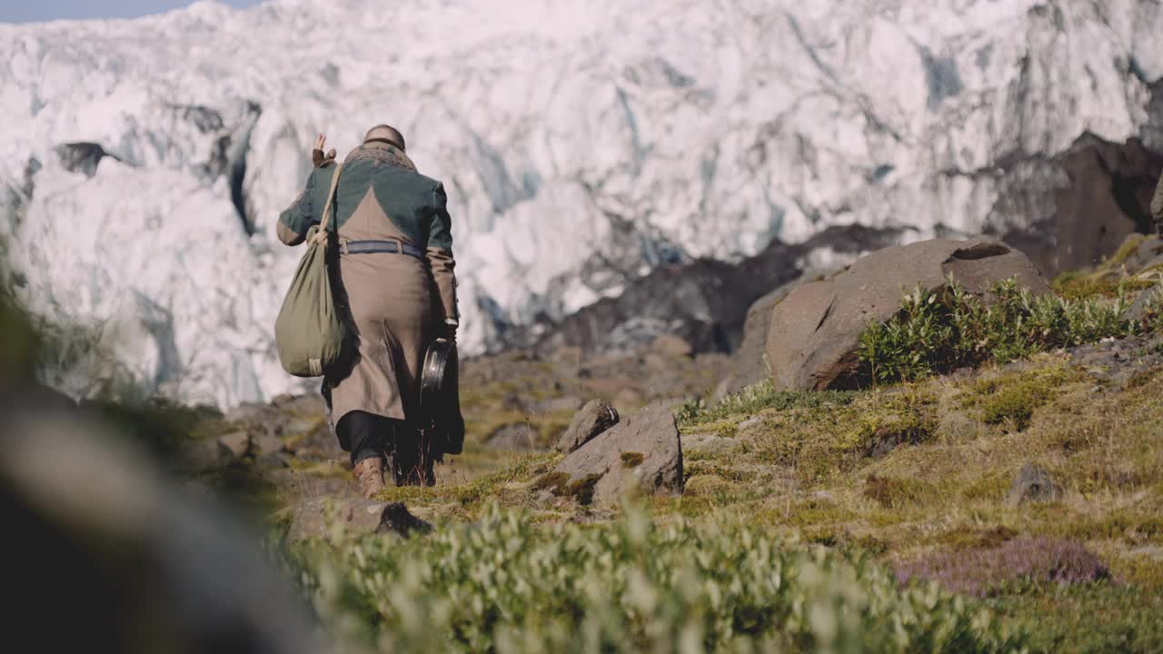 旅行者携带吉他盒在岩石山旁边的冰川视频素材