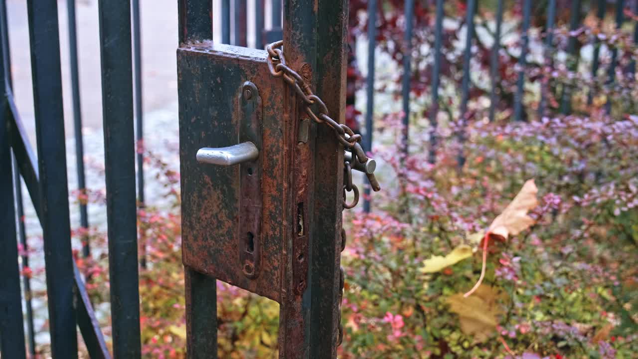 生锈的金属财产栅栏门，损坏的锁和坏的把手与铁链和简单的挂锁视频素材