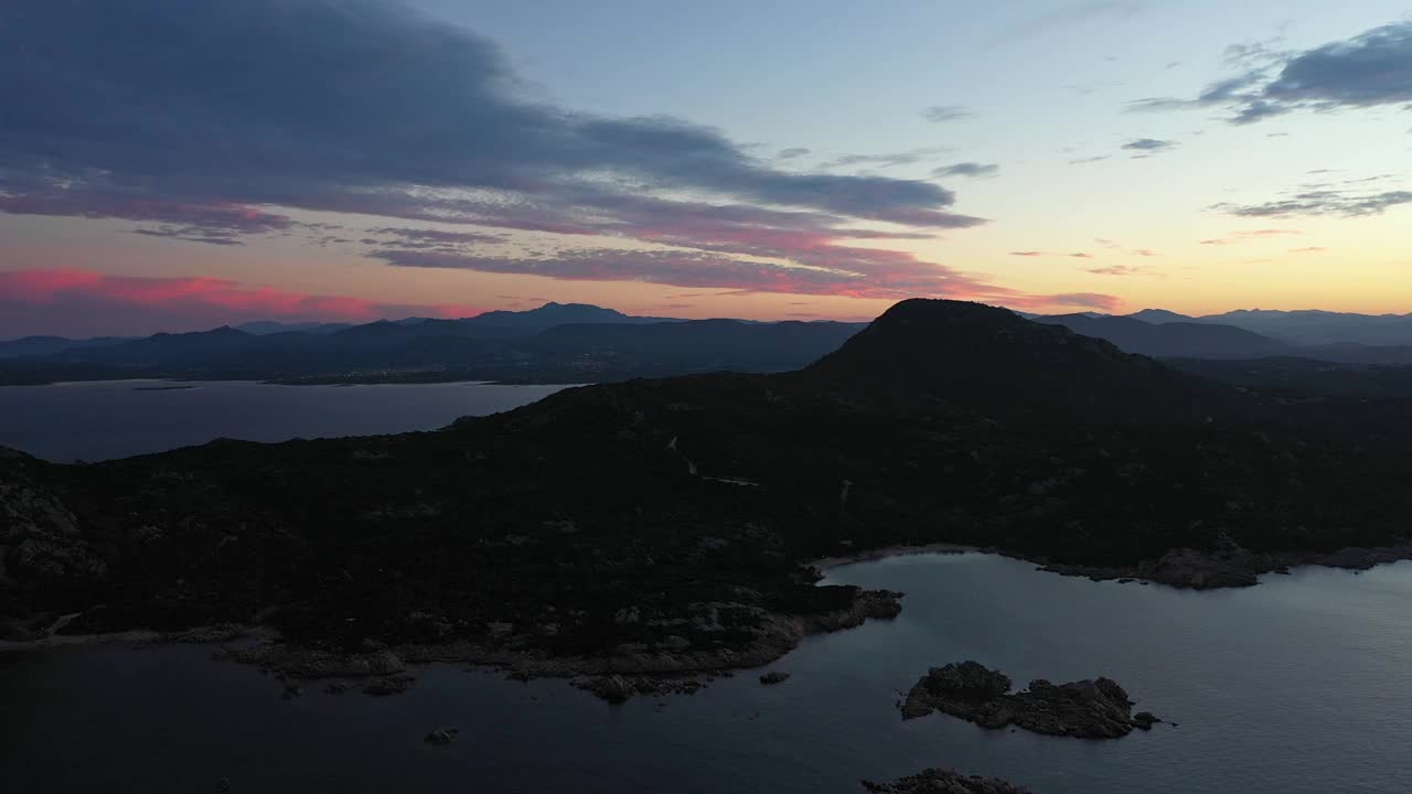 从上面看，令人惊叹的鸟瞰海岸线沐浴在平静的水在美丽的日落。意大利撒丁岛的卡波塞拉索。视频素材