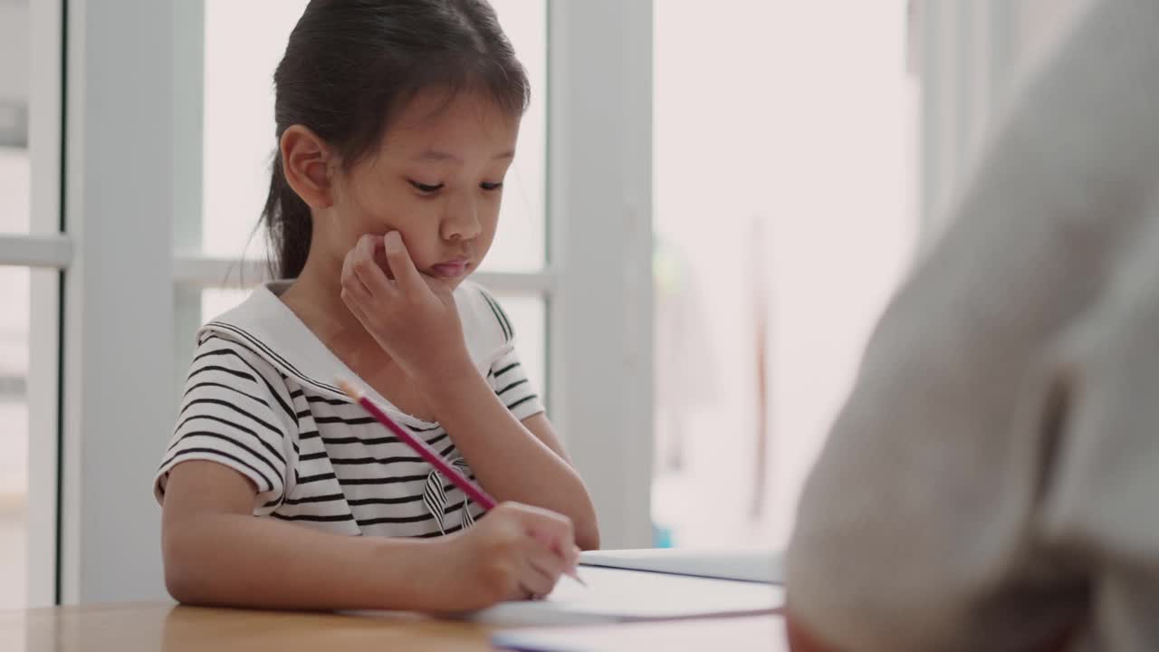 亚洲小女孩在家学习用铅笔写字视频素材