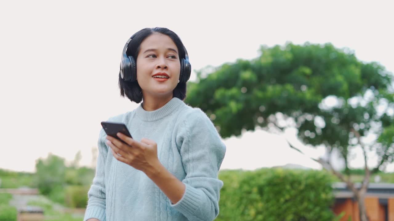 亚洲女人用耳机听音乐视频素材