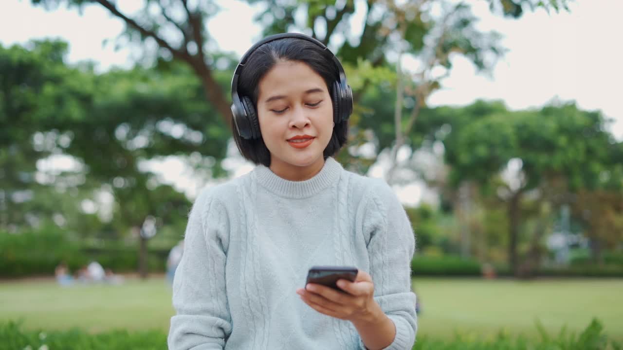 亚洲女人用耳机听音乐视频素材