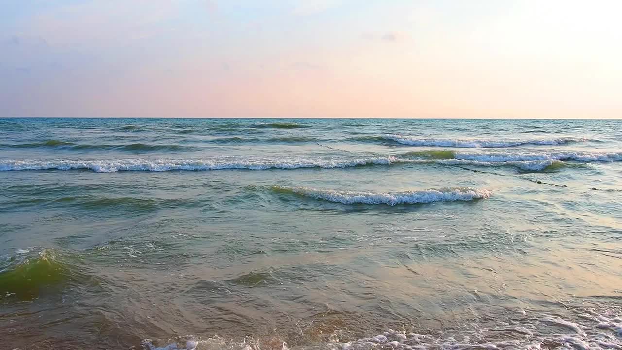 平静的波浪卷过沙滩。海上日落。水的运动。海浪汹涌着泡沫。旅游的天堂。透过海水可以看到沙子。旅游海滩主题视频素材