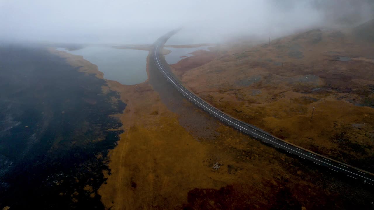 无人机在雾天被水包围的冰岛公路上跟踪汽车。视频素材