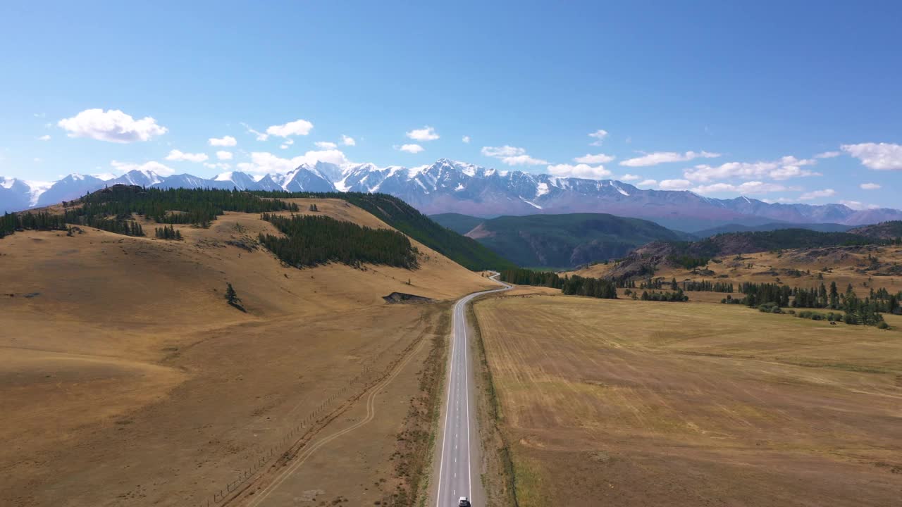 沿着柏油路行驶的车辆驶向雪山视频素材