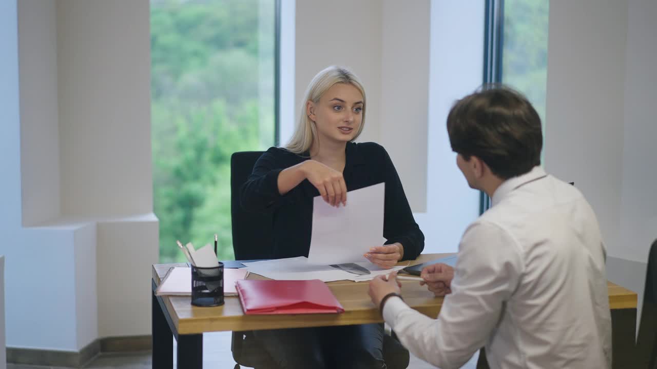 年轻微笑的女人在求职面试申请表上签字。积极的白人人事经理用慢动作解释责任和职责。视频素材