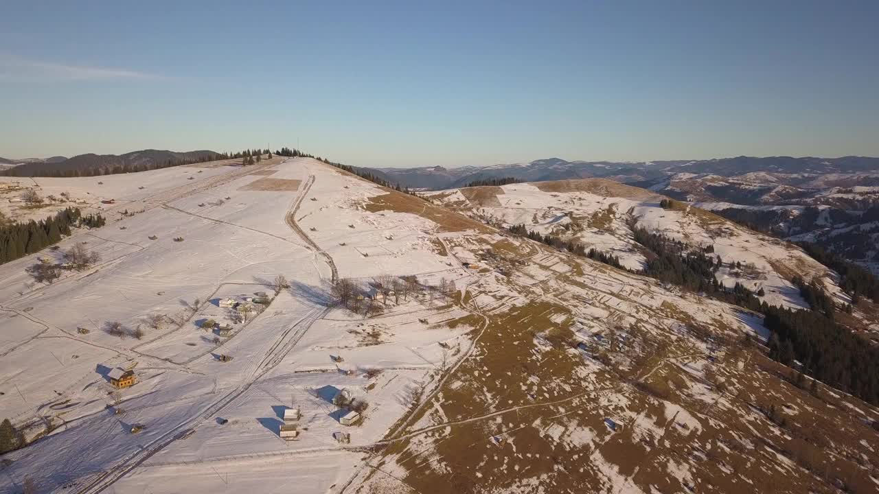 鸟瞰图小村庄与散落的房屋在冬季积雪覆盖的小山和裸露的喀尔巴阡山脉在乌克兰。视频素材