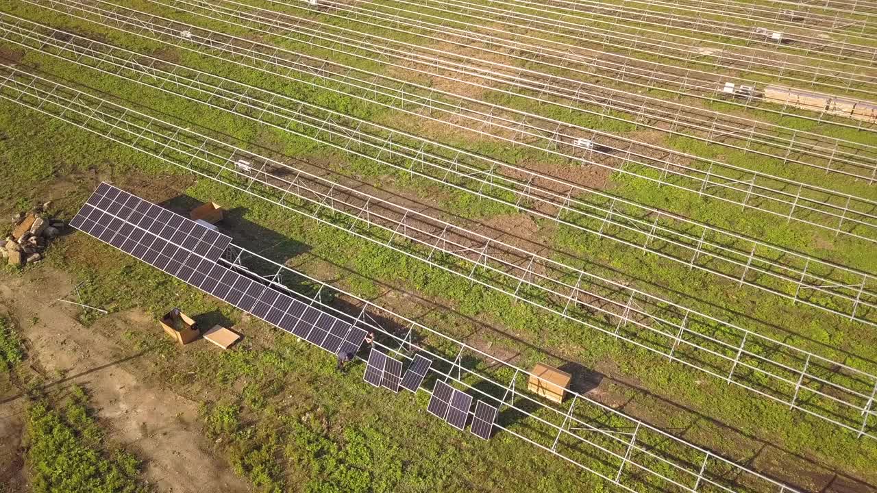 绿地上正在建设的太阳能发电厂鸟瞰图。生产清洁生态能源的电板组装。视频素材