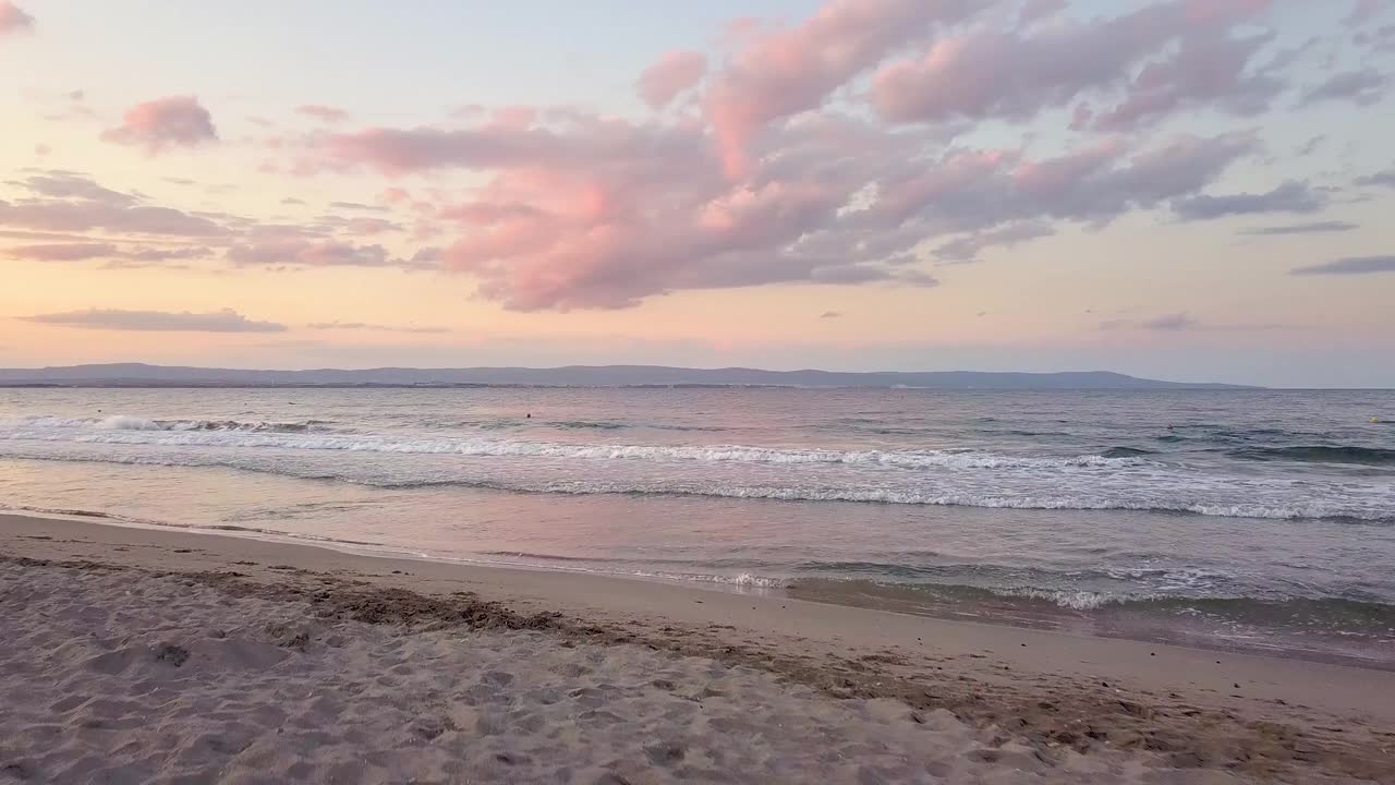 鸟瞰图的海面与蓝色的波浪在紫色的日落天空下。视频素材