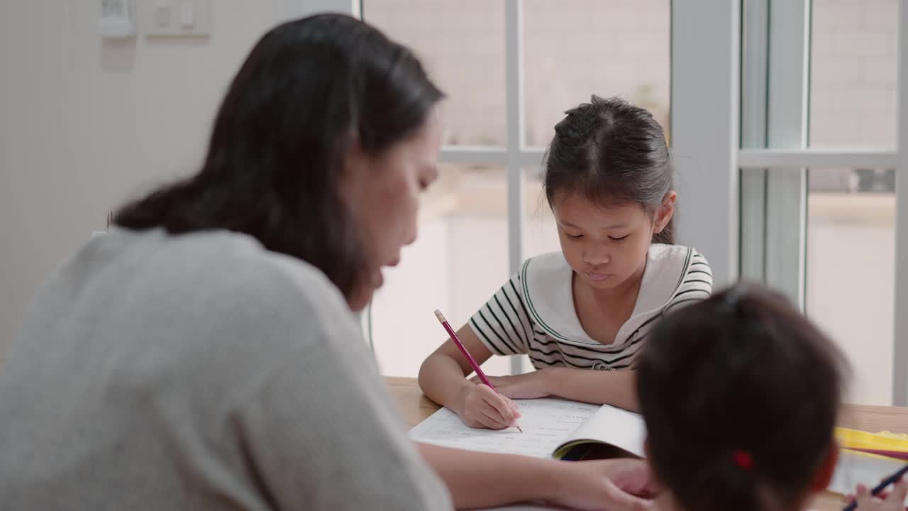 母亲照顾两个女儿在家学习，照顾姐姐视频素材