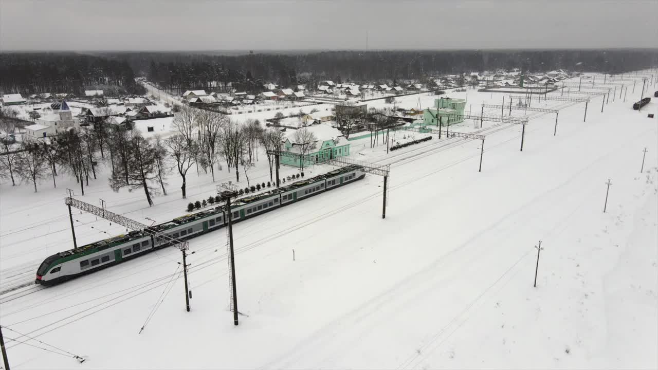 城际现代电动火车行驶在积雪覆盖的铁轨上视频素材