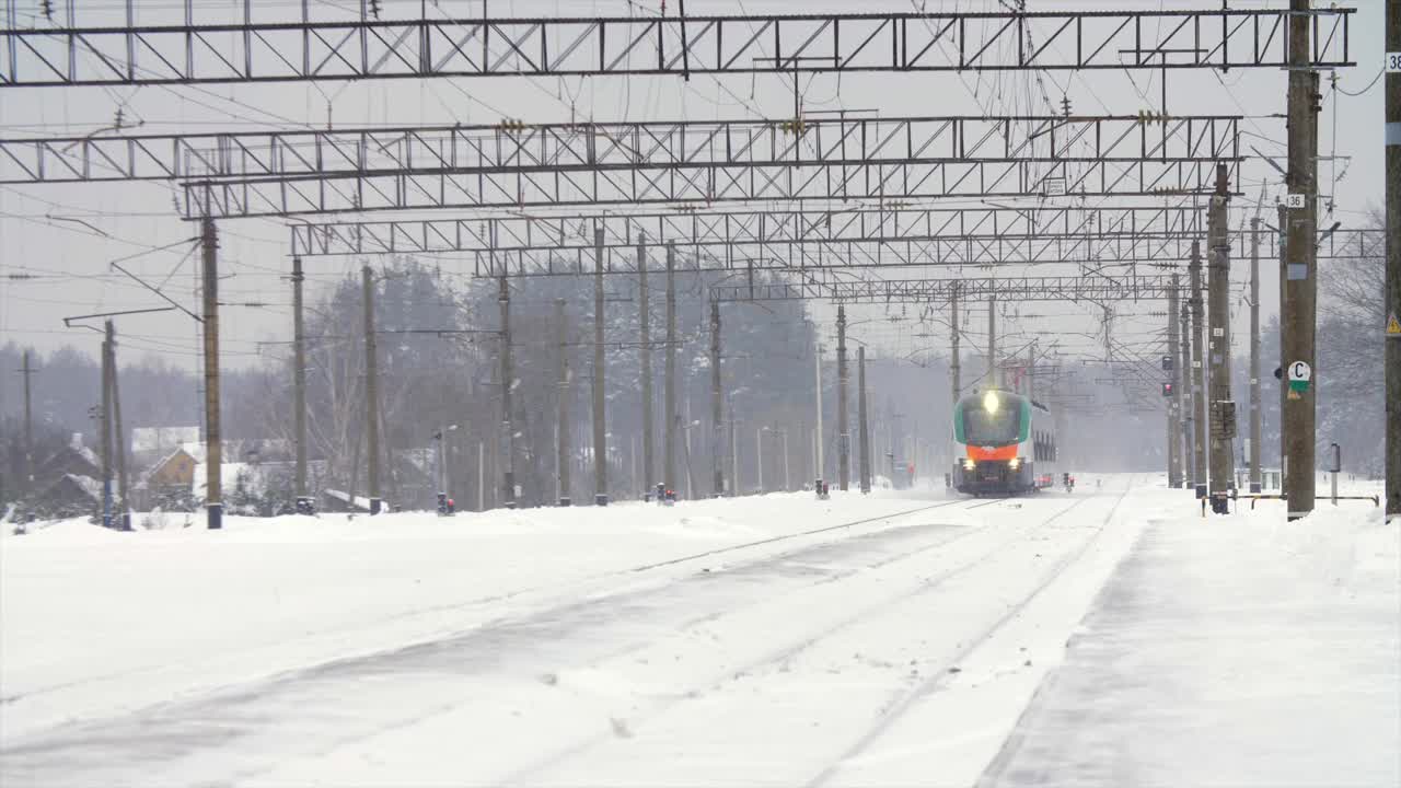 城际现代电动火车行驶在积雪覆盖的铁轨上视频素材