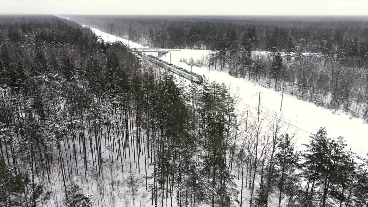 城际现代电动火车行驶在积雪覆盖的铁轨上视频素材